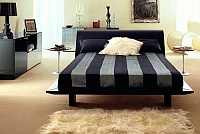 Кровать Fold. Linee sinuose che si rincorrono per tutta la testata. La sensazione che si percepisce è una grande eleganza e ricchezza. Tutta la superficie di questo letto è ricoperta di cuoio. I supporti posteriori ed i piedi sono in rovere scur